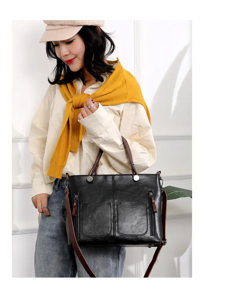 Black leather tote crossbody bag with large capacity brown straps and silver toned hardware in retro style.