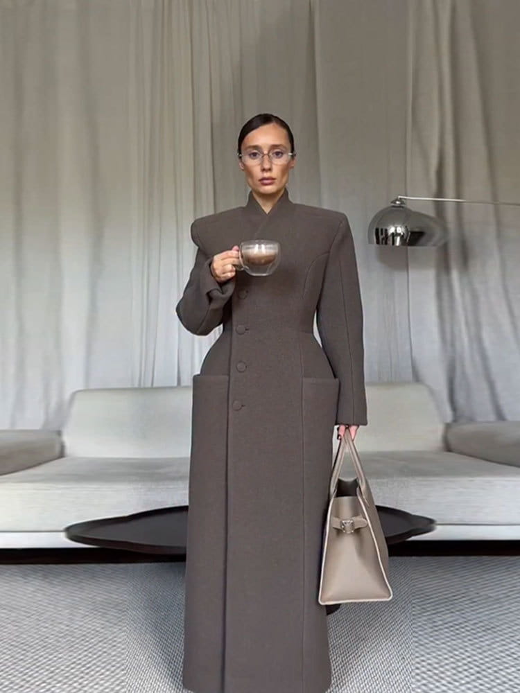 a taupe structured wool coat for women with exaggerated shoulders and a high collar in a charcoal gray waisted long outerwear style