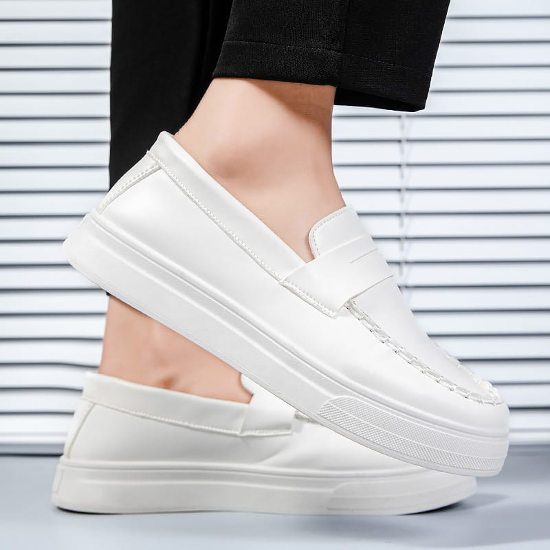 Mocasines blancos de cuero, tipo slip-on, con suela de goma blanca gruesa y de aspecto robusto, y detalles de costura discretos.