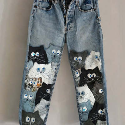 Blue denim cat print faux denim flared trousers featuring a playful patchwork of black white and gray cat appliqués with embroidered eyes.