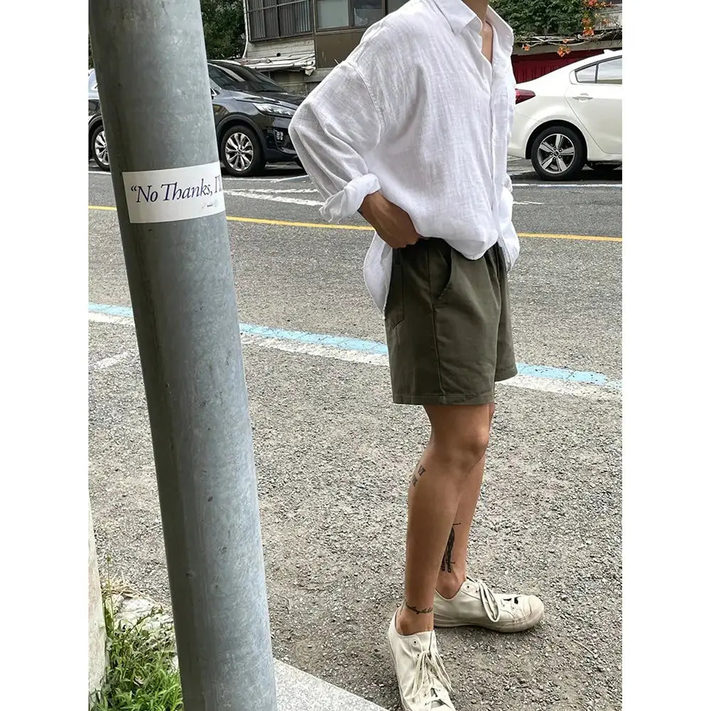 olive green cargo shorts with side pockets and a relaxed fit paired with a korean style white linen button up shirt.