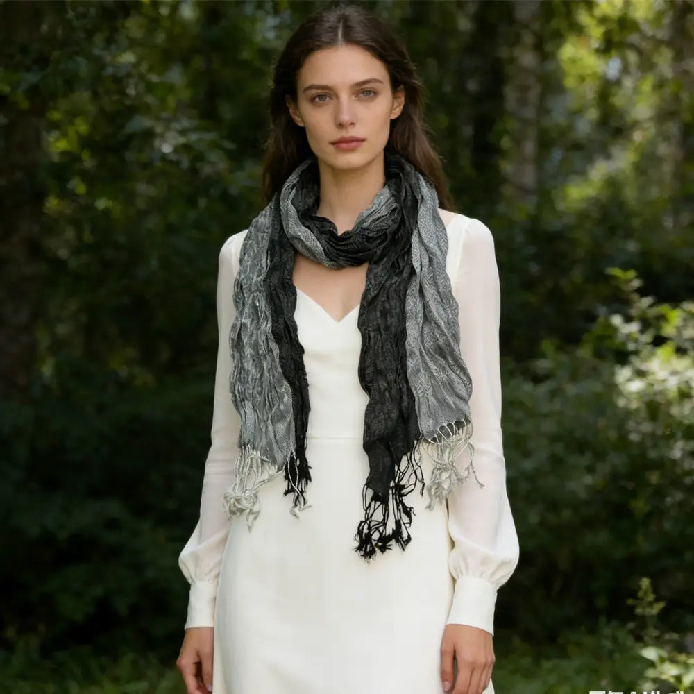 Écharpe longue d’hiver en polyester jacquard dégradé gris et noir, texturée, avec des bords effilochés, portée autour du cou pour femmes.
