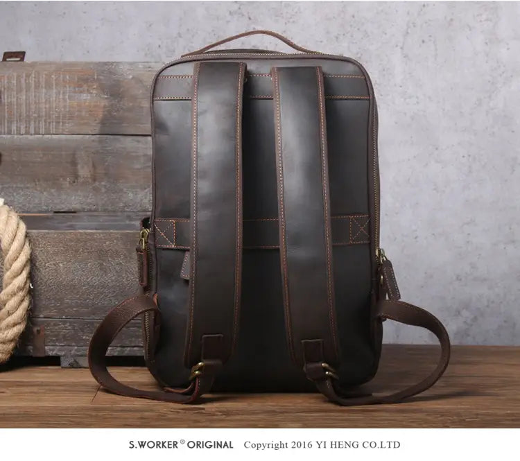Men’s vintage leather backpack in dark brown cowhide featuring contrasting tan stitching and adjustable shoulder straps shown from the back.