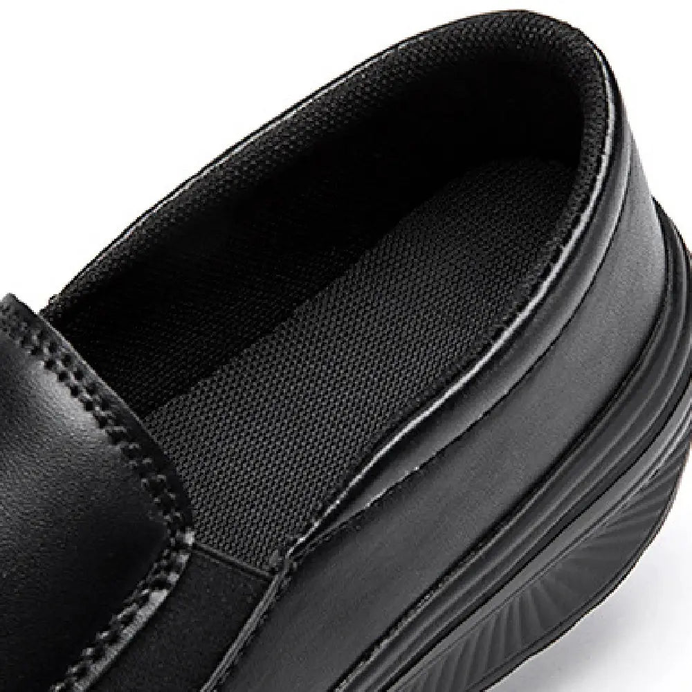Chaussure slip-on à talon compensé en forme de coin en cuir noir, avec semelle intérieure texturée et semelle côtelée.