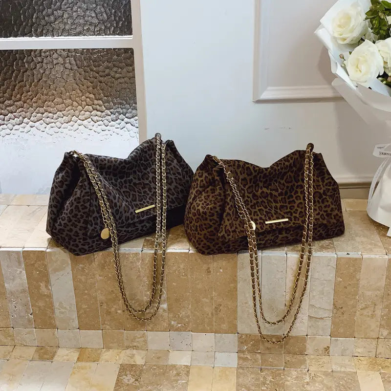 Two leopard print crossbody bags with gold chain straps in darker and lighter brown tones.