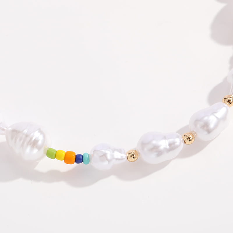 A delicate necklace from the layered gold butterfly and pearl jewelry set for women featuring irregularly shaped white pearls with small gold-toned beads and a vibrant rainbow-colored bead cluster.