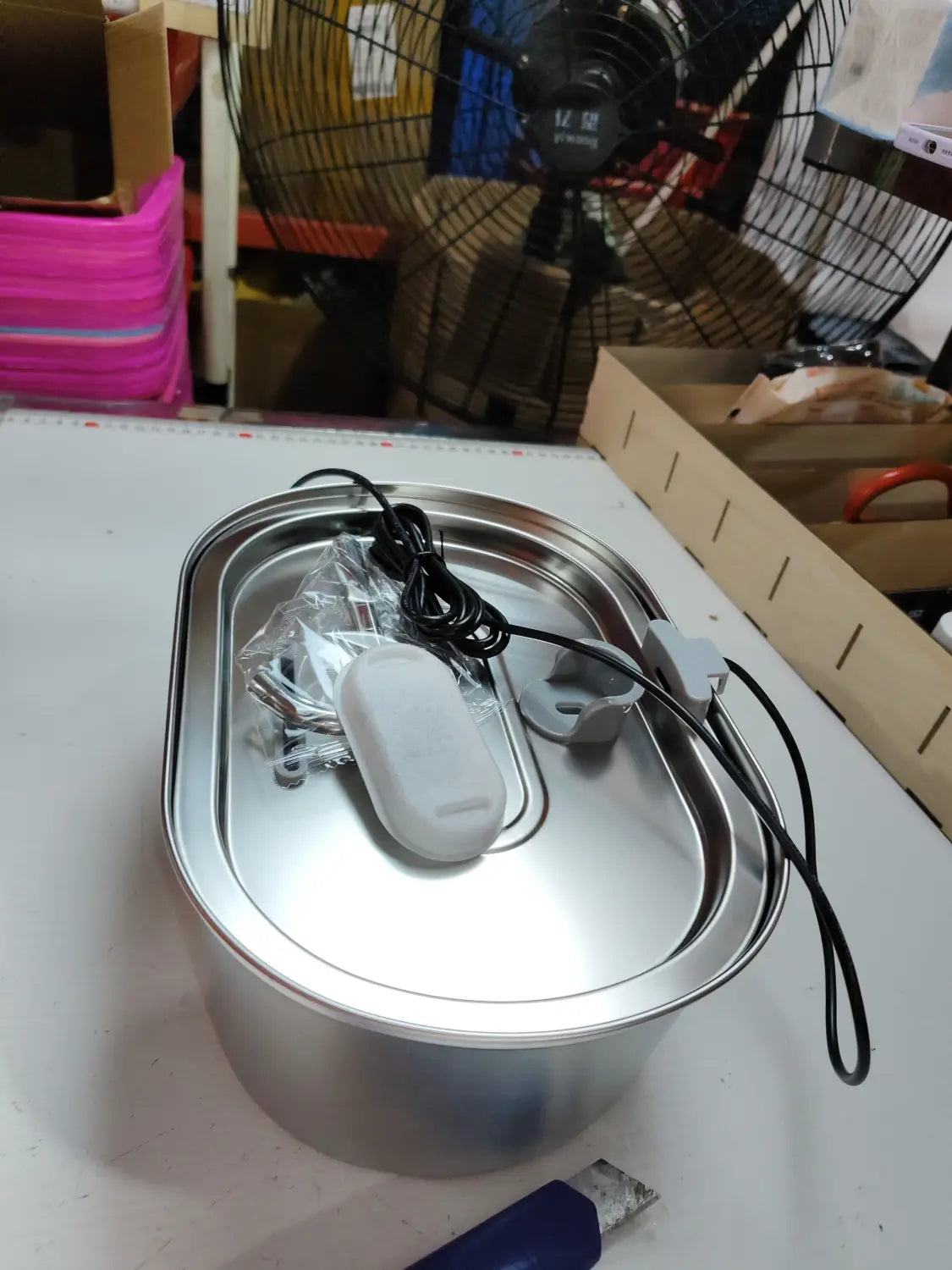 Oval geformter Edelstahl-Ultraschallreiniger für Haustiere mit Filter und elektrischer Funktion, mit weißer Steuereinheit und schwarzem Netzkabel, ausgelegt für die Verwendung als Trinkbrunnen mit Filter.