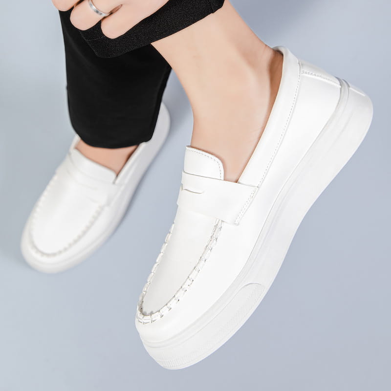 Mocasines blancos de cuero, tipo slip-on, con suela de goma blanca gruesa y de aspecto robusto, y costuras contrastantes.