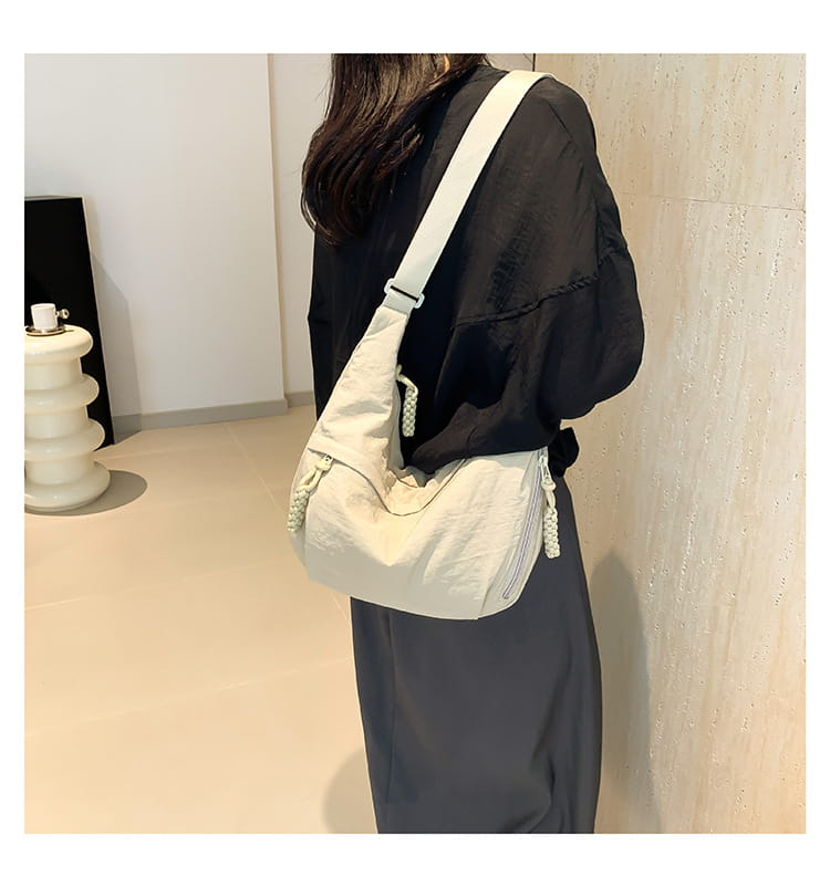 Cream-colored nylon crossbody bag large capacity hobo shoulder bag with braided rope detailing on the zipper pulls and strap.