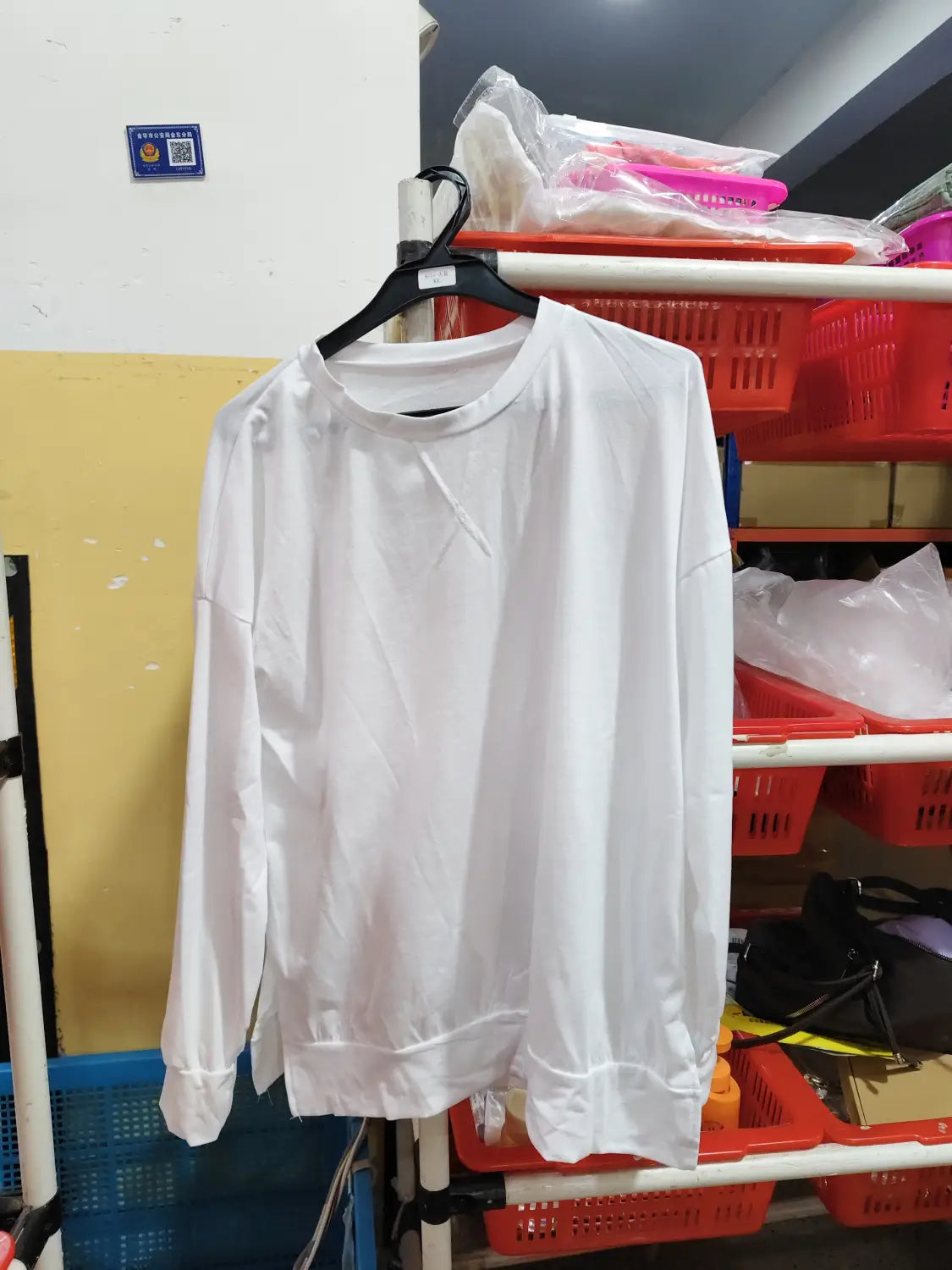 White long-sleeved crewneck split front relaxed knit sweater hanging on a black hanger.