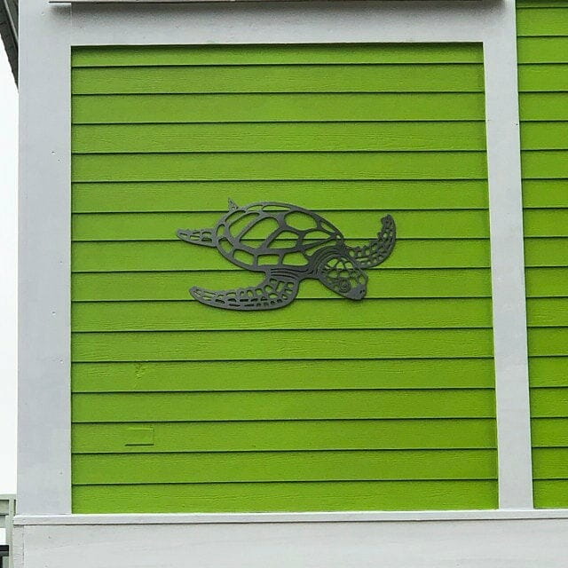 Metall-Wandskulptur mit Schildkrötenmotiv, mit aufwendig gestalteten Aussparungsmustern und einer dunkelgrauen Metalloptik, für eine minimalistische Deko zum Thema Meerestiere.