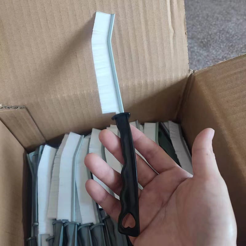 black-handled metal edge trim with a white corrugated plastic strip included in a 5-piece set of gap cleaning brushes for tile and crevice cleaning
