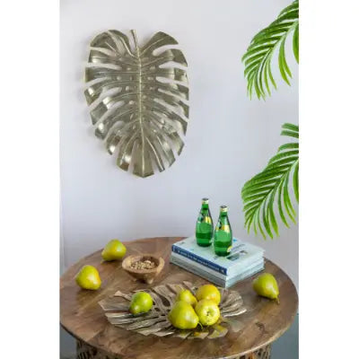 Silver metallic monstera leaf wall art featured in gold monstera leaf wall decor and serving tray set.