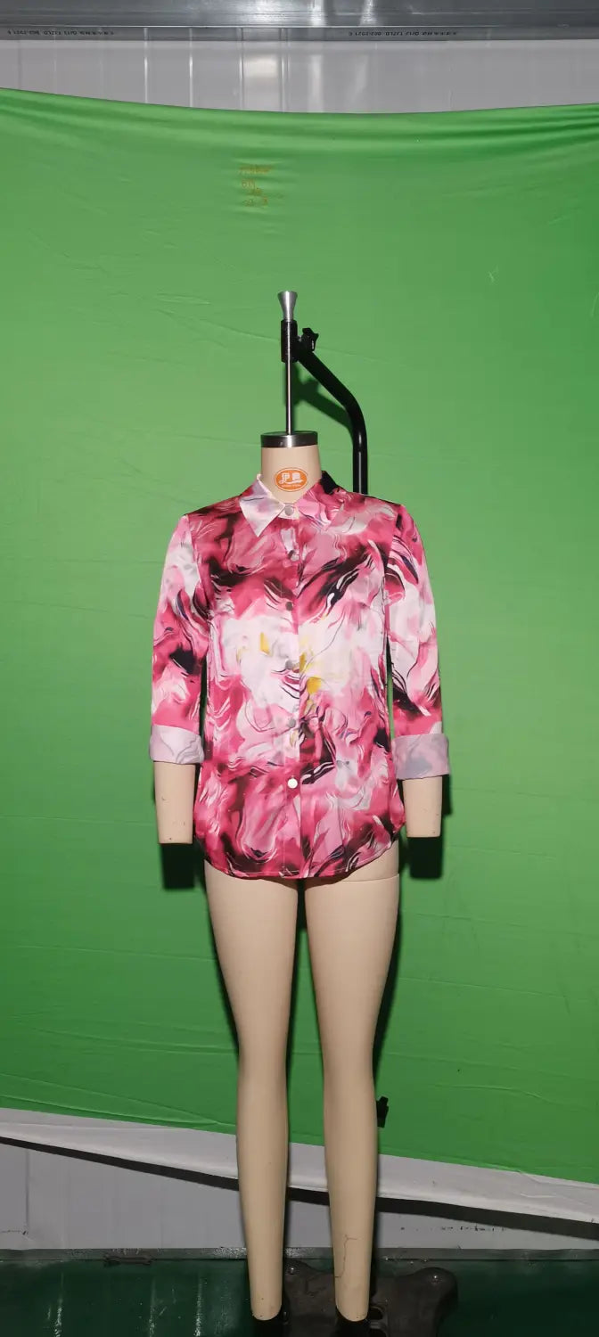 A pink floral-patterned satin blouse with three-quarter sleeves and a button-down front displayed on a mannequin.