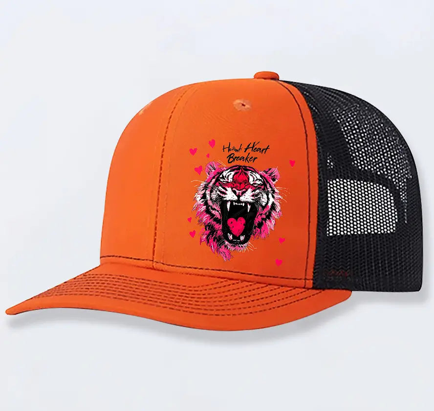 Vibrant orange and black tiger graphic trucker hat for men with pink accents red heart details and heart breaker embroidered text.