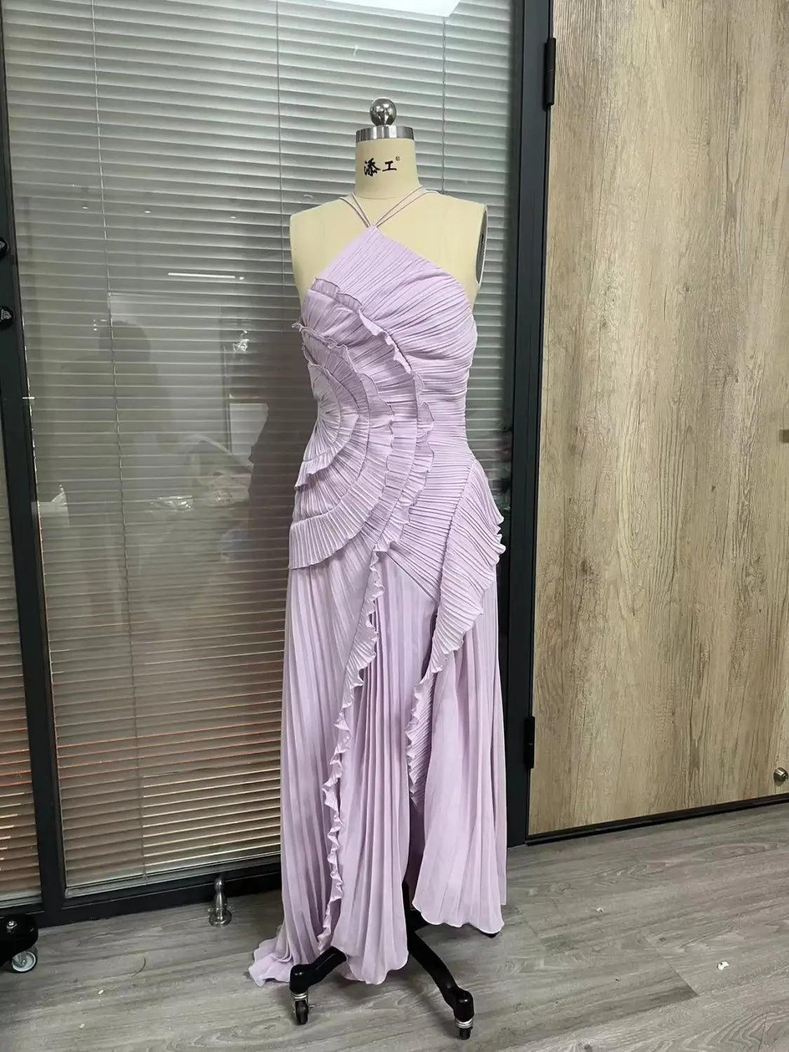 A lavender pleated chiffon evening gown featuring layered ruffles and a one-shoulder asymmetrical halterneck design.