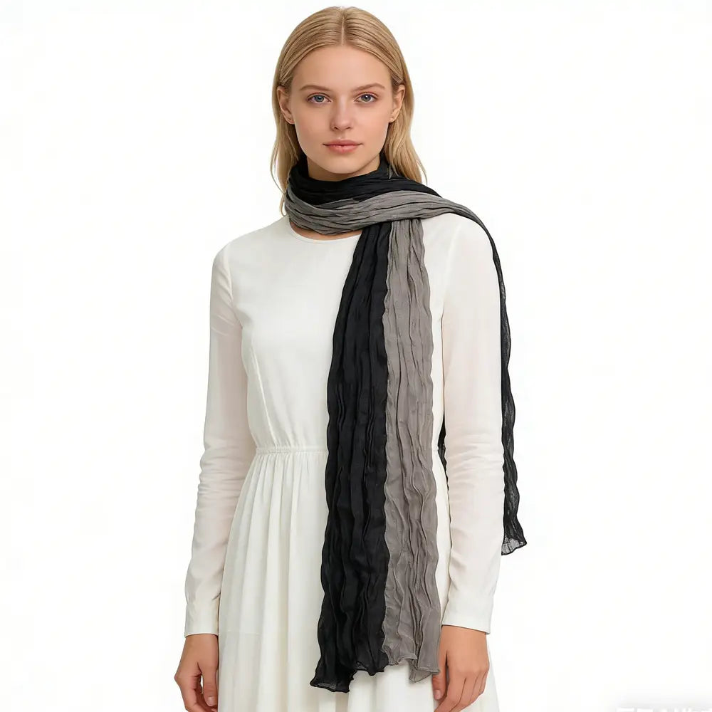 Una bufanda con textura acanalada suave y color gris negro, con apariencia arrugada, drapeada con elegancia alrededor del cuello.