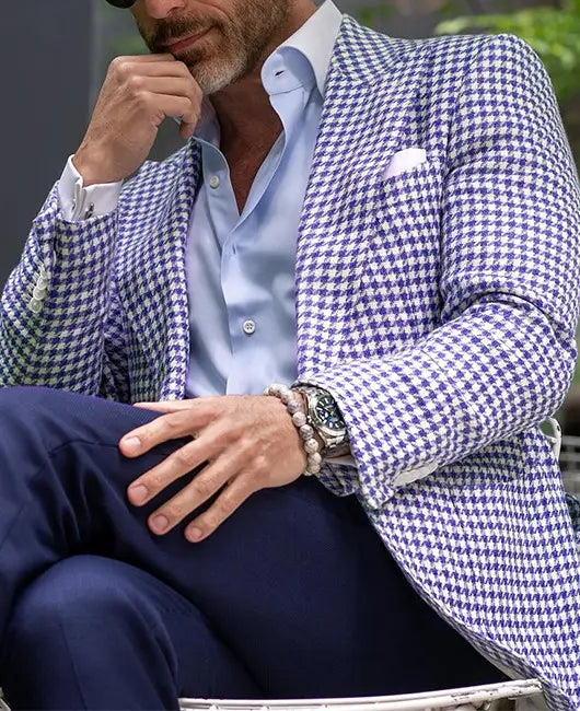 Ein Mann, der eine blau-weiße Hahnentritt-Slim-Fit-Anzugjacke trägt, mit passendem Einstecktuch.