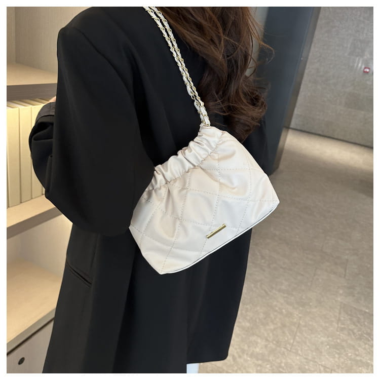 white quilted faux leather crossbody bag with silver chain shoulder strap displayed from the front.