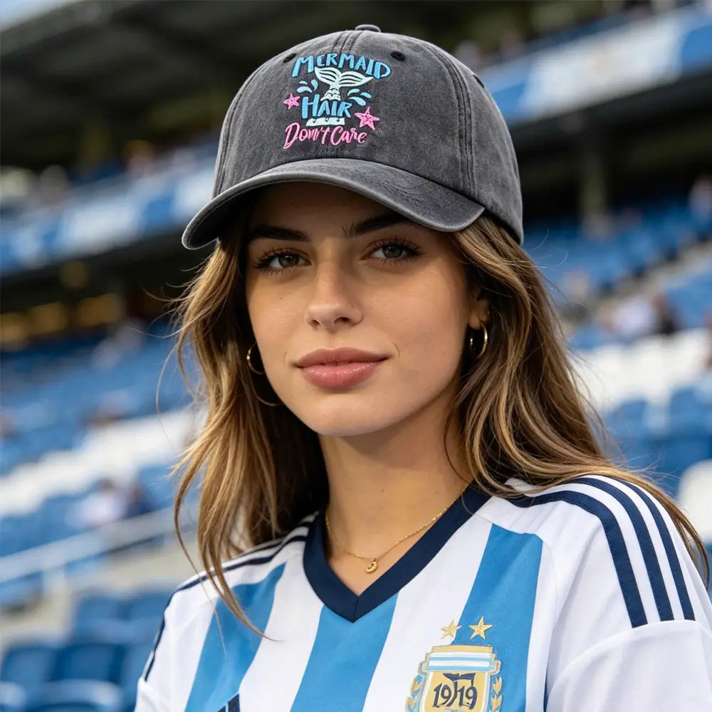 Una gorra tipo béisbol de algodón gris desgastado con texto bordado azul y rosa que dice el cabello de sirena, no me importa, con acentos de estrellas.