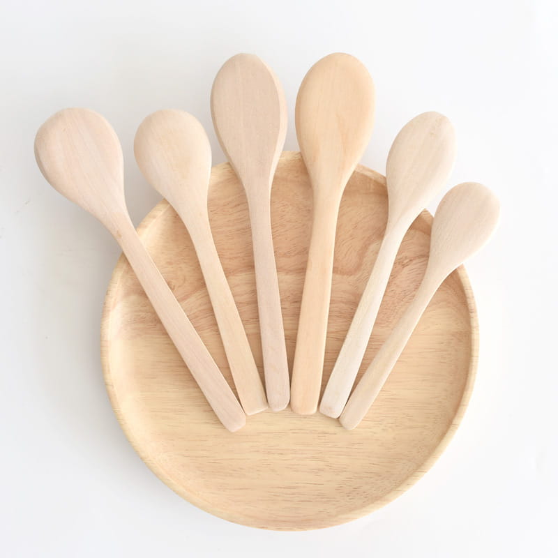 Set of six natural-finish wooden spoons made from eco-friendly material arranged on a matching round wood plate for kitchen utensils.