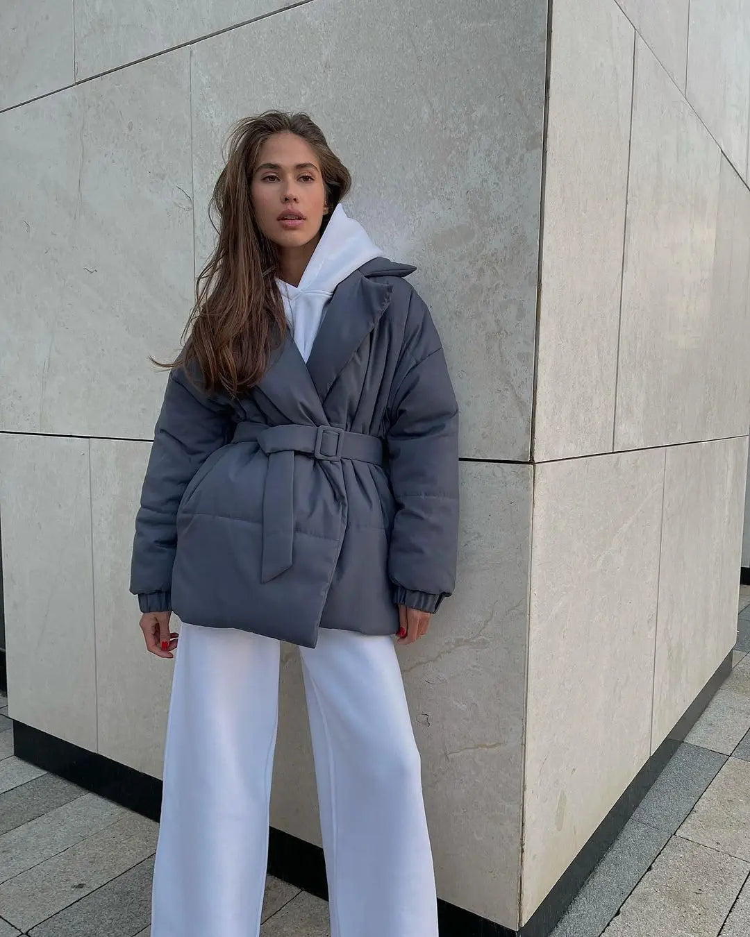 Damen-Gurtsteppjacke mit Kapuze, wattierte Pufferjacke in Grau mit Taillengürtel und weißem Innenfutter für die Kapuze, für Winterbekleidung konzipiert.
