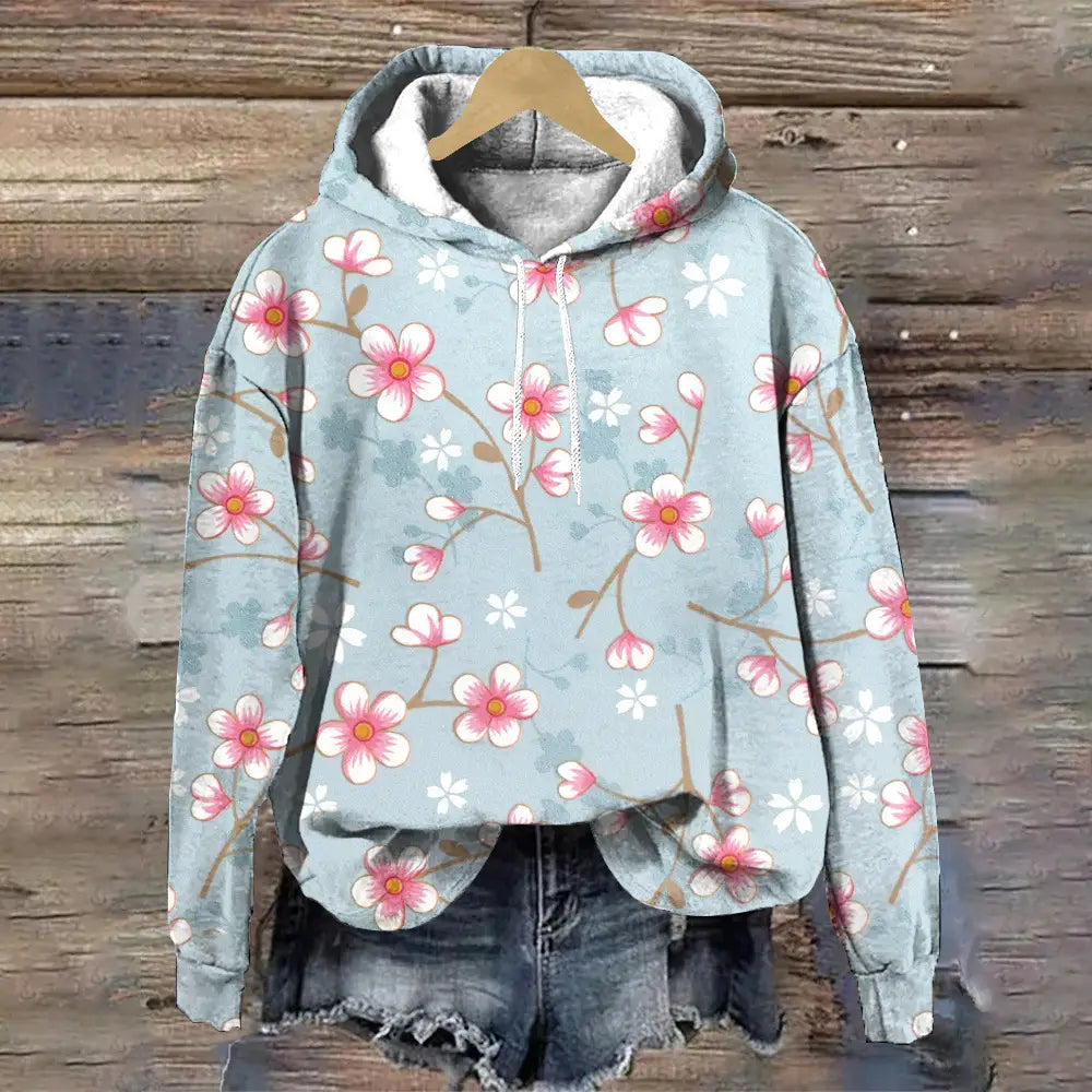 Sudadera con capucha de ajuste holgado con estampado floral en azul claro con patrón de flor de cerezo rosa y blanco, que presenta una capucha forrada de gris acogedor y cordones.