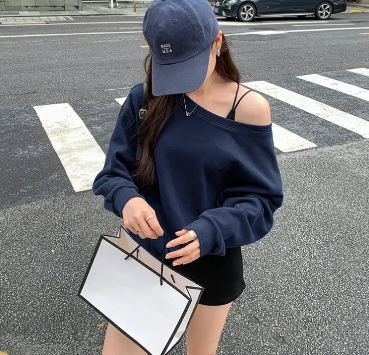 Navy blue women’s loose off the shoulder ribbed knit sweater with long sleeves and ribbed cuffs.