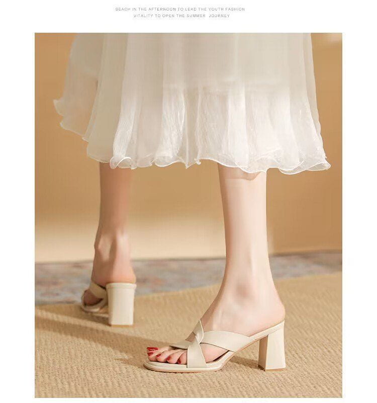 Cream-colored leather mule sandals with a chunky heel and a crisscross strap design for stylish open toe wear.