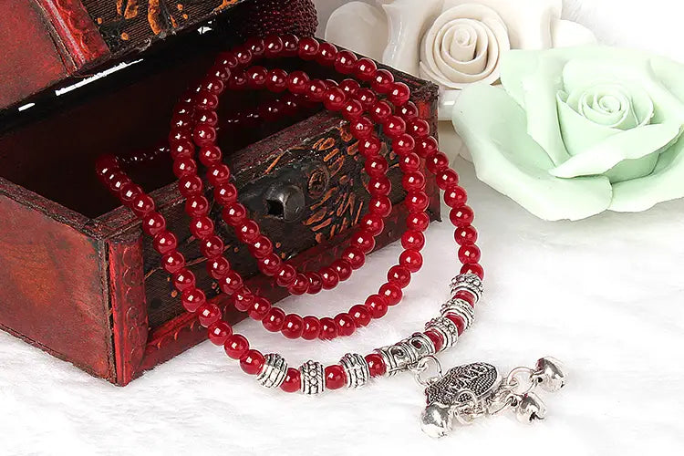 Red agate good luck bracelet featuring a red beaded design with a silver-toned turtle charm and decorative spacer beads.