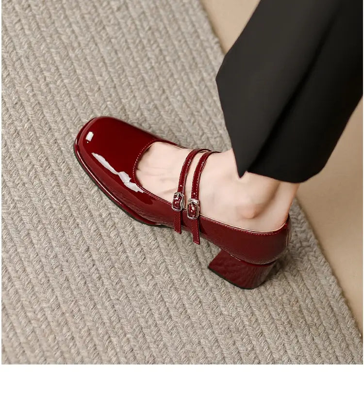 A glossy burgundy patent leather mary jane shoe featuring a square toe block heel and double strap buckle detail.