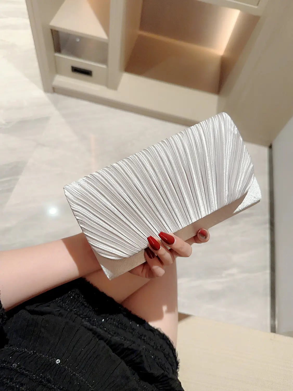 Silver pleated clutch with a sleek modern design and subtle metallic sheen in satin material ideal for minimalist women’s evening bag.