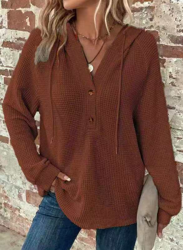 A cozy rust-colored waffle-knit women’s v neck hoodie sweater with front button closure and drawstring hood.