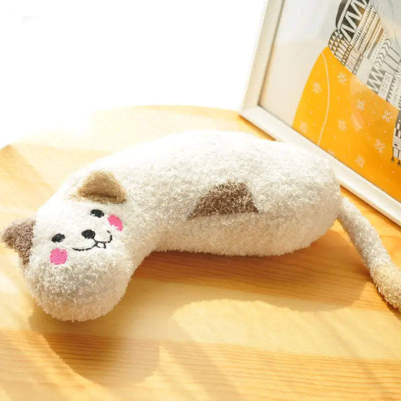 Ein plüschiges Kissen in Weiß und Beige in Katzenform mit rosa Wangen und bestickten Gesichtszügen, ausgelegt für Nackenunterstützung und Gelenkentlastung.