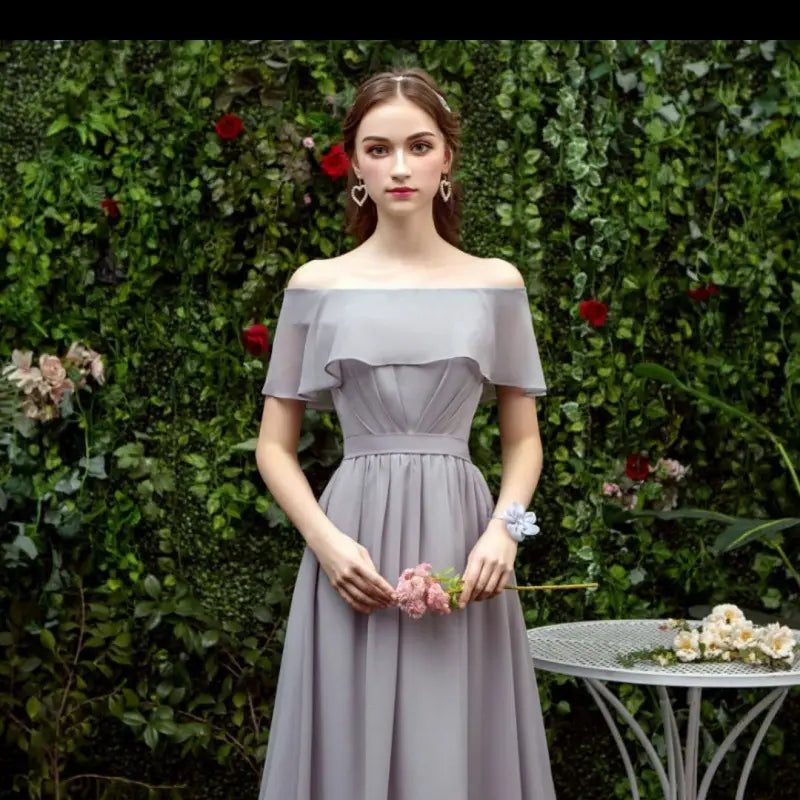 A woman wears an off-the-shoulder gray chiffon midi dress with ruffled sleeves and a fitted waist suitable as a bridesmaid gown.