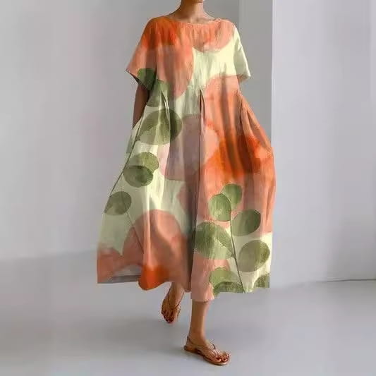 Robe longue en lin grande taille à coupe A, à imprimé floral, fluide et ample, dans un mélange doux de pêche et de crème, avec de grands motifs de feuilles vertes.