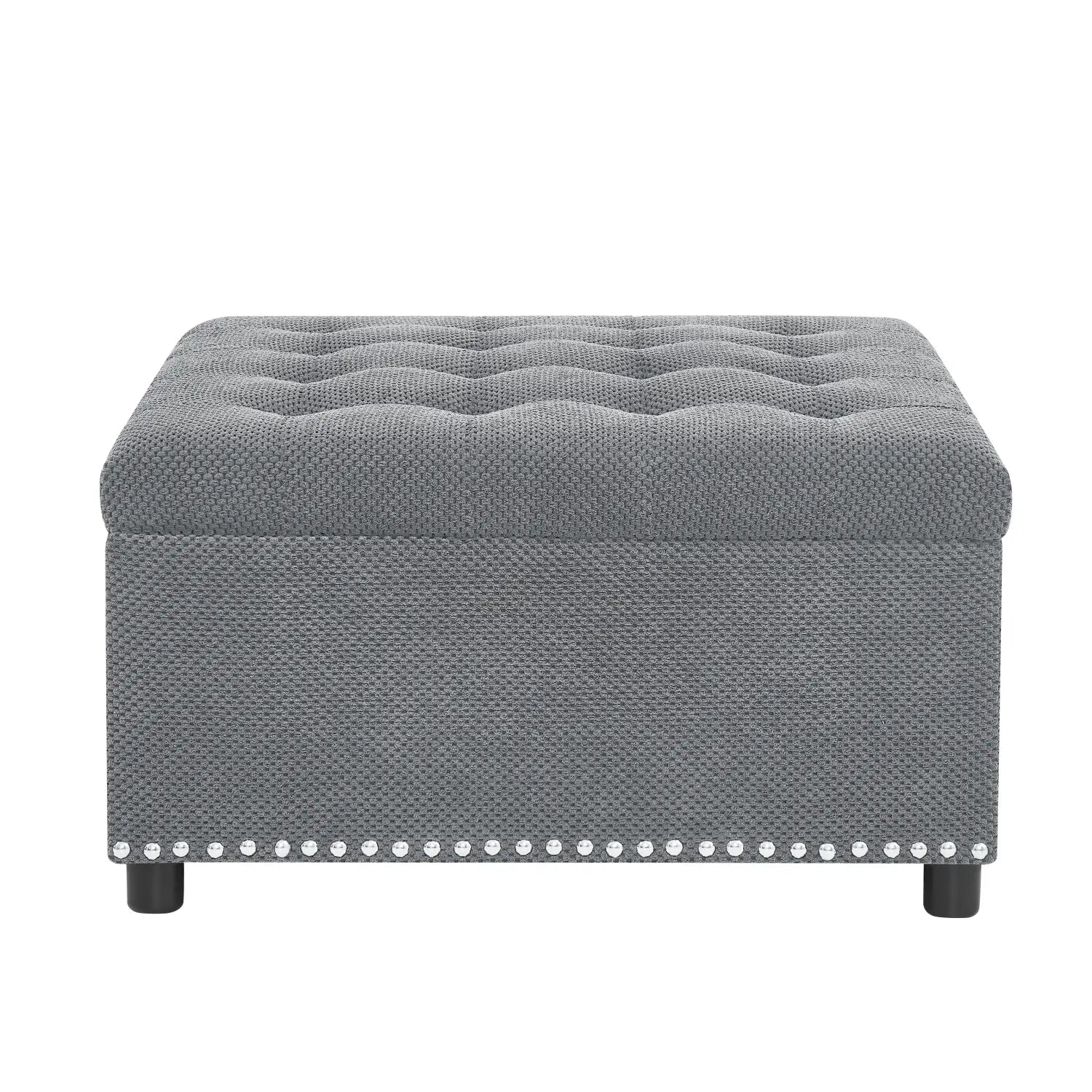 Gray tufted storage ottoman with textured fabric finish and decorative silver nailhead trim along the base.