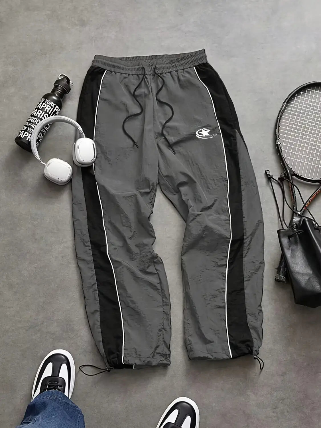 Men quick dry athletic track pants in gray with black side panels and white piping featuring a drawstring waistband and elastic cuffs.