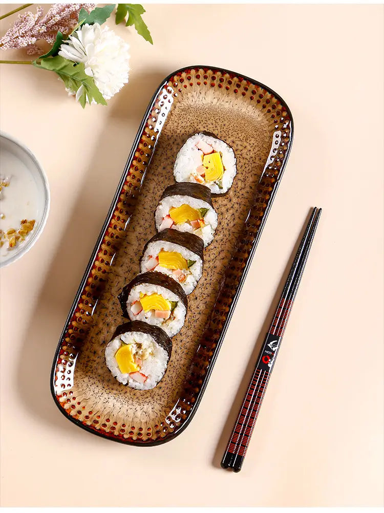 Brown ceramic serving tray 12.5 inch rectangular platter with speckled texture and dotted rim holding six sushi rolls.