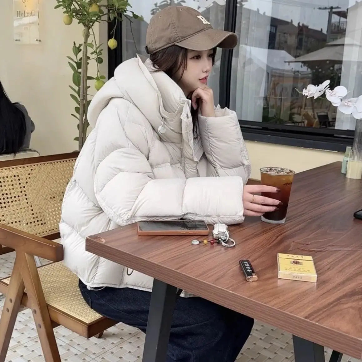 Una chaqueta acolchada de plumón blanca marfil, cómoda, con cuello alto y diseño acolchado, destacada como chaqueta de invierno acolchada de plumón morada para mujer.
