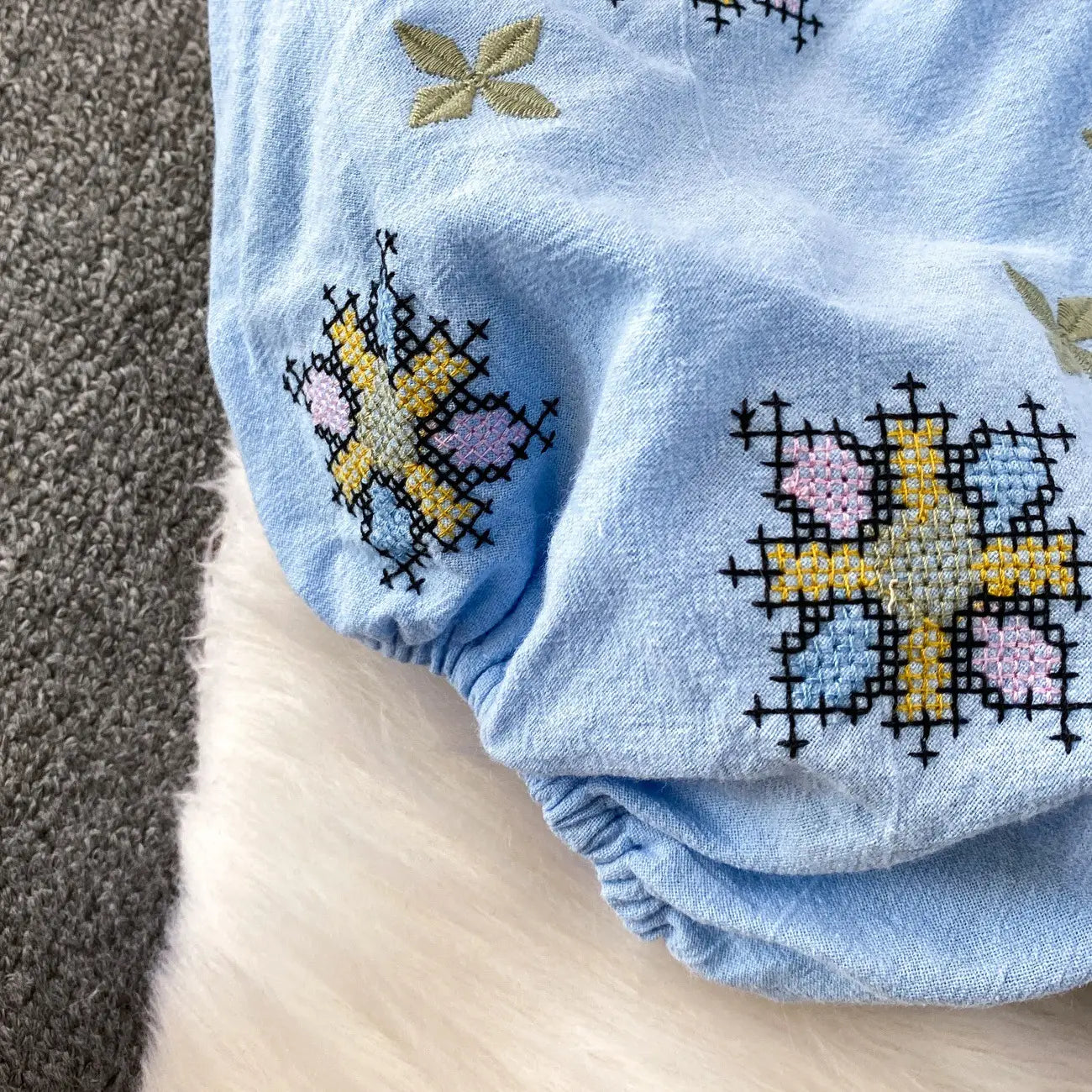 Light blue cotton embroidered lantern sleeve tie neck blouse with colorful cross-stitched floral patterns in yellow pink and light blue