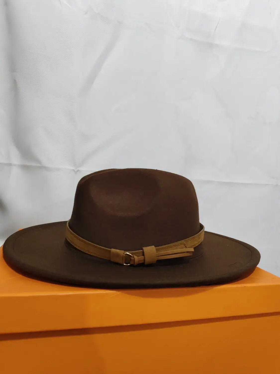 Brown wool fedora hat featuring a tan leather strap and buckle detail.