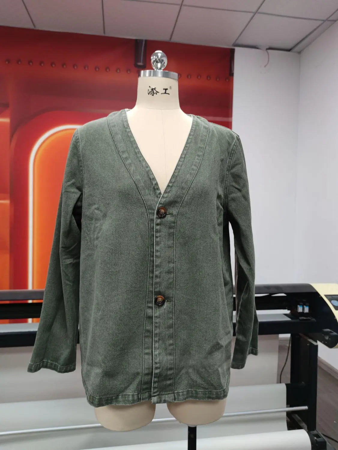 Chaqueta tipo cárdigan de mezclilla color verde oliva para mujer con diseño de cuello en V y cierre oscuro con botón color marrón oscuro.