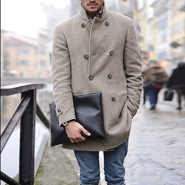 a black leather clutch held in a mans hand paired with a men woolen double breasted mid length coat