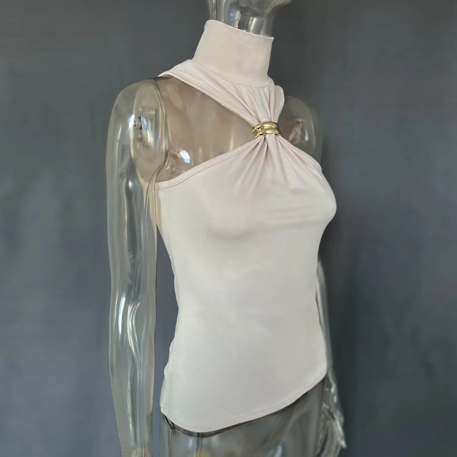 A sleek off-white knit gold ring halter stretch top with a high neckline and asymmetrical shoulder design accented by a gold-toned metal ring.