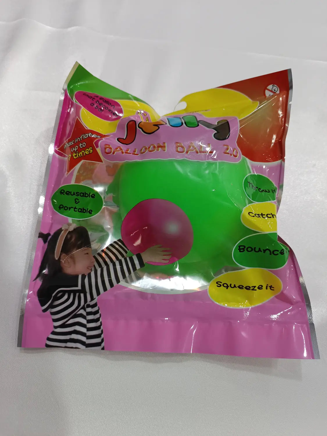 Una bola hinchable de burbuja gigante de TPR, de color verde y rosa, tipo globo de agua elástico, en un envase de plástico colorido, con un material elástico similar al caucho para apretar y rebotar.