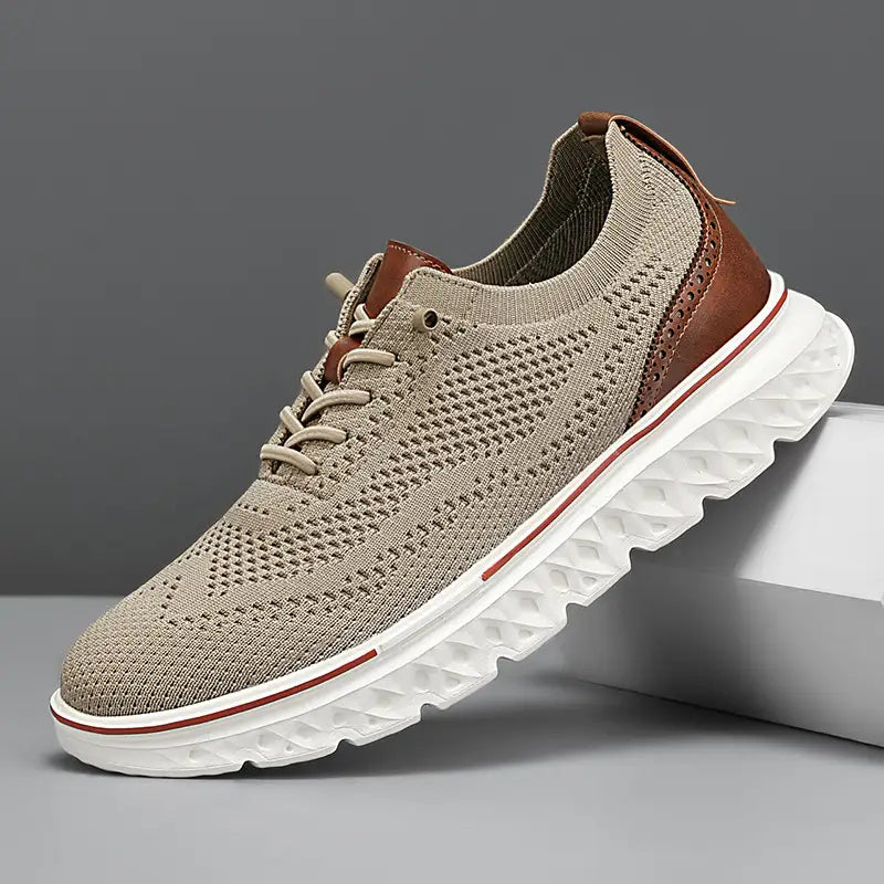 Men’s mesh knit casual lightweight sneaker in beige with brown leather accents and a white rubber sole featuring red trim.