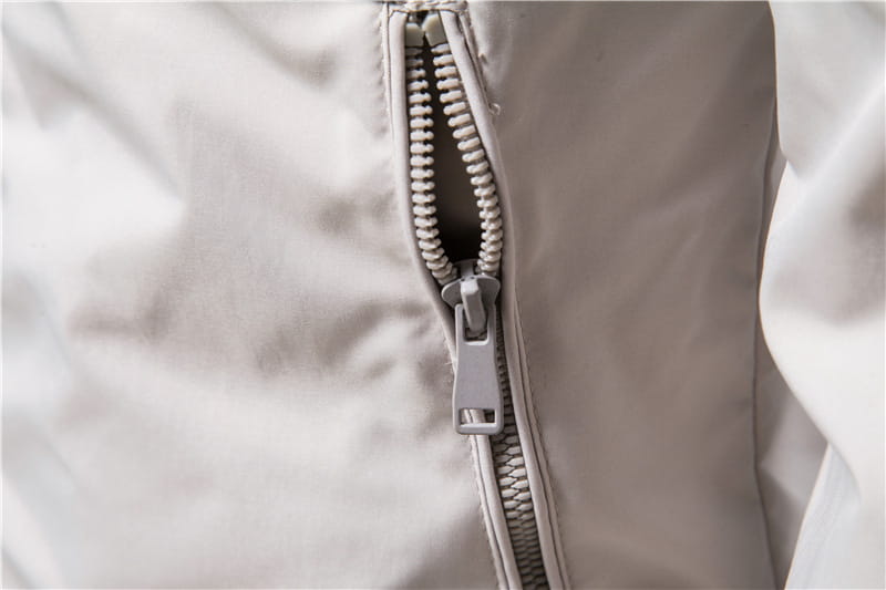 A sleek light gray zipper with a matching pull tab runs vertically along the seam of a smooth white fabric men’s bomber jacket casual zip outerwear.