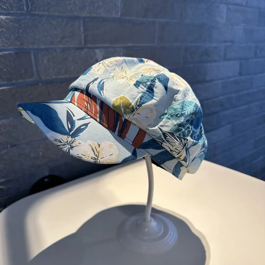 A stylish floral newsboy cap for women featuring a soft light blue fabric base with vibrant teal orange and cream botanical prints.