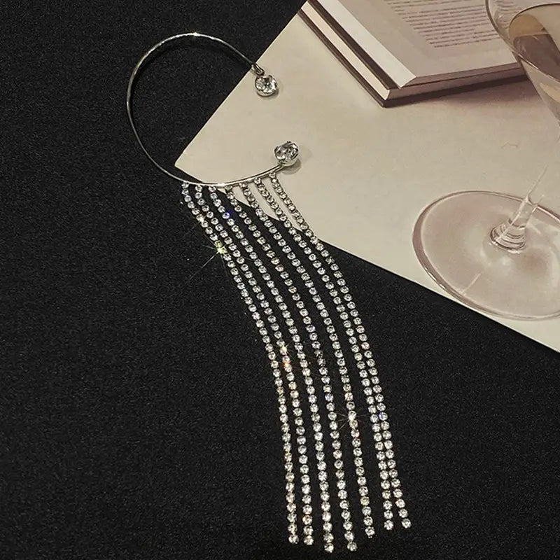 Silver rhinestone fringe ear cuff with a curved metal band and cascading strands of clear crystals paired with crystal tassel 14k gold plated long drop earrings.